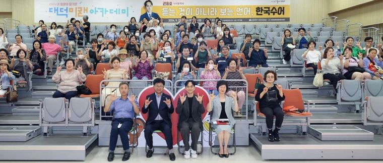 최충규 대덕구청장, 권동호 수어통역사, 그리고 지역 주민들이 강연을 마친 후 기념사진을 촬영하고 있다.